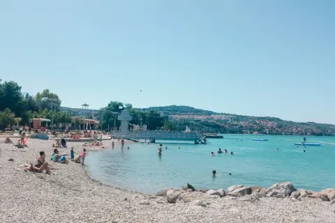 Plaża w Słowenii, ludzie kąpią się w morzu. Odpowiedź na pytanie: czy Słowenia ma dostęp do morza? Tak, ma!