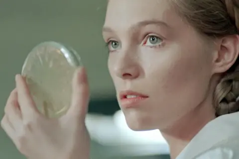 Młoda kobieta z warkoczem ogląda szalkę Petriego. Scena z filmów Małgorzaty Braunek.
