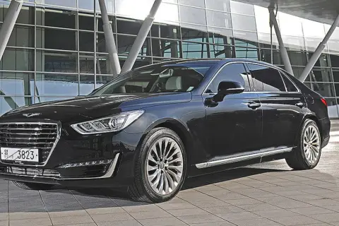Elegancki, czarny Genesis G90 lśni przed nowoczesnym budynkiem.