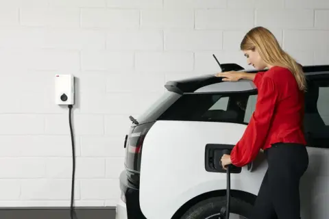 Femme branchant sa voiture électrique sur une borne. Une solution pratique pour le crédit d'impôt borne électrique.
