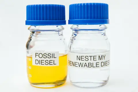 Två provrör med blå korkar. Ett innehåller gulaktig fossil diesel, det andra klar Neste my renewable diesel.