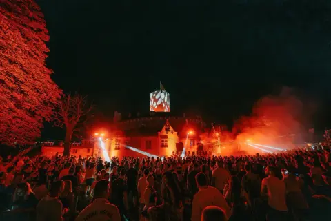 Nocny festiwal w twierdzy z tłumem ludzi i pokazem świateł.