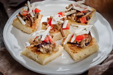 Deliziosi crostini con melanzane, pomodoro e scaglie di formaggio su pane tostato.