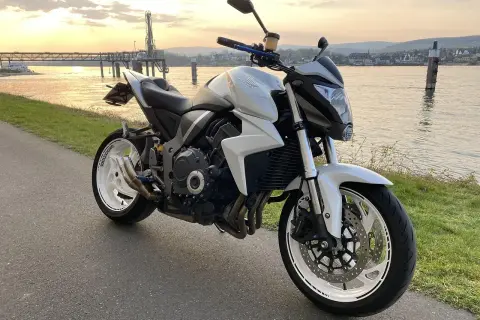 Biały motocykl turystyczny Honda zaparkowany nad rzeką o zachodzie słońca.