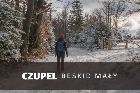 Kobieta z plecakiem idzie zimowym szlakiem w Beskidzie Małym. To czupel najładniejszy szlak, pokryty śniegiem.