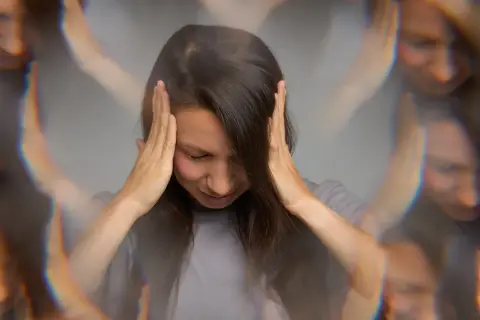 Vrouw met handen op haar hoofd, gezicht vertroebeld, wat de mentale kater na alcohol symboliseert.