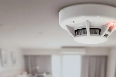 Détecteur de fumée blanc au plafond, voyant rouge allumé. Il est temps de changer la pile de ce détecteur de fumée insafe.