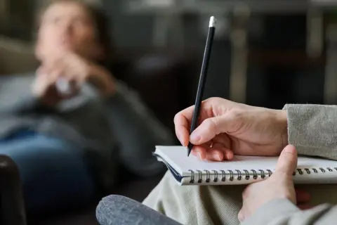 Psycholog słucha i notuje, pomagając pacjentowi zrozumieć siebie.
