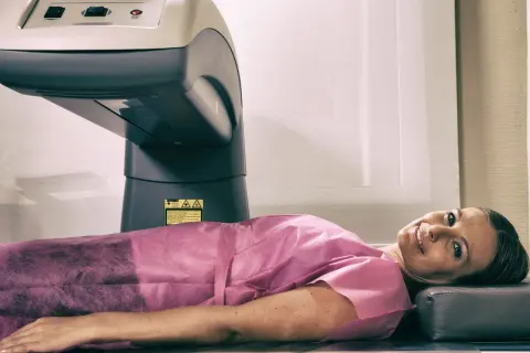 Kobieta leży pod aparatem do densytometrii, badanie wykrywa osteopenię.
