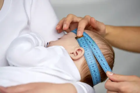 Dziecko mierzone centymetrem. Wynik można porównać z obwód główki niemowlaka tabelą.
