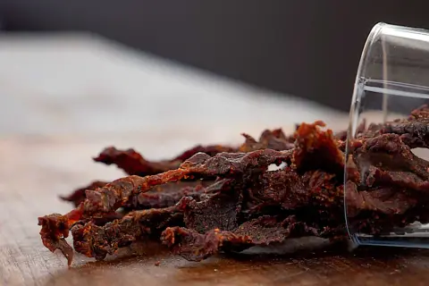 Leckeres beef jerky selber machen ist gar nicht schwer! Hier ist ein Haufen selbstgemachtes Beef Jerky, das aus einem Glas gekippt wurde.