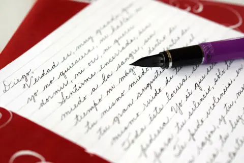 A purple fountain pen rests on a letter written in elegant cursive, demonstrating how to write it in cursive.
