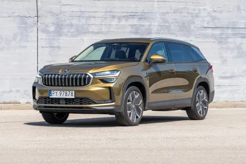 Złoty Skoda Kodiaq stoi przed betonową ścianą. Poznaj jego imponujące skoda kodiaq wymiary, idealne na rodzinne podróże.