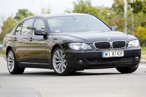 Eleganckie czarne BMW 730d na polskich tablicach WI 8743F jedzie po drodze, otoczone zielenią.