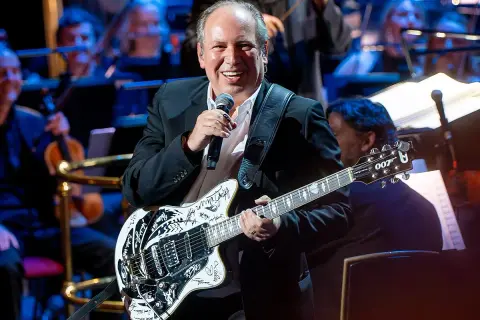 Hans Zimmer z gitarą, która brzmi jak ścieżka dźwiękowa do jego filmów. Uśmiechnięty kompozytor na scenie z orkiestrą.