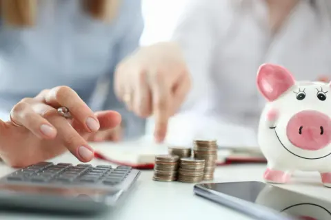 Osoby analizują finanse, liczą monety i patrzą na skarbonkę. Rozważają inwestycje, takie jak obligacje indeksowane inflacją, by chronić oszczędności.