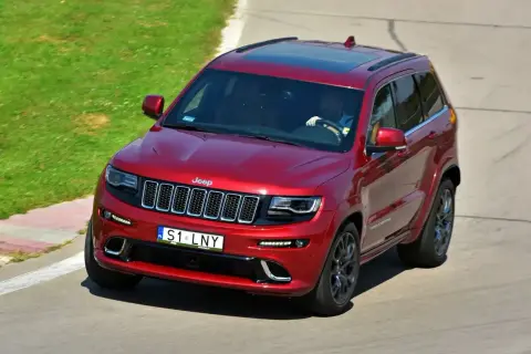 Czerwony Jeep Grand Cherokee z indywidualnymi tablicami rejestracyjnymi "S1 LNY" na torze wyścigowym.