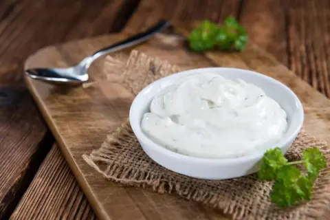 Cremige Sour Cream in einer Schale, bereit zum Dippen. Ein Löffel liegt daneben.