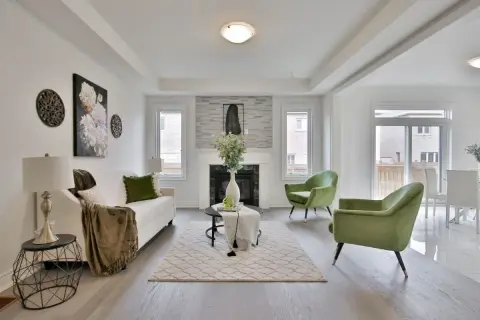 Salon moderne avec canapé blanc, fauteuils verts et une cheminée. La deco de table noir et or ajoute une touche d'élégance.
