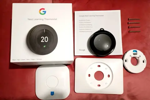 Kit pour l'installation d'un thermostat Nest Learning. Boîte, manuel, thermostat, socle et vis.