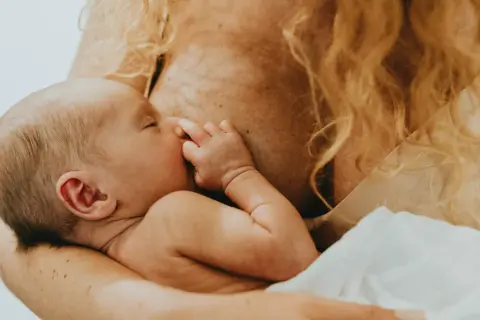 En bebis ammas, med handen vid munnen. En lugn stund för mamma var tredje timme.