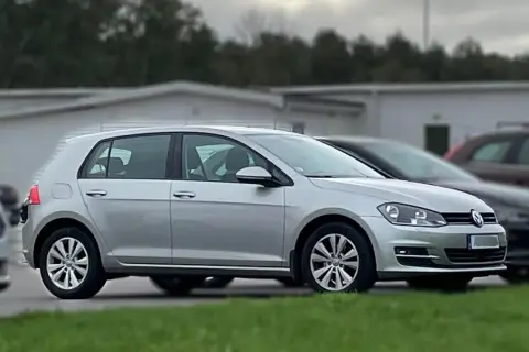 Silver tsi golf parkerad på en gräsmatta framför en vit byggnad.