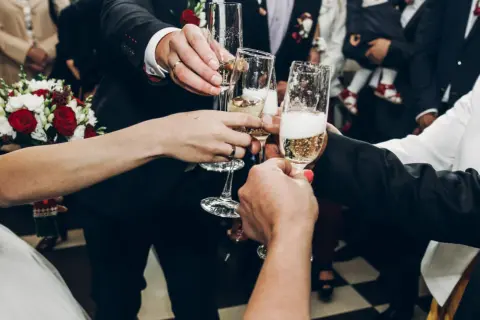 Para wznosi toast kieliszkami szampana. Zastanawiasz się, ile wódki na wesele? To zdjęcie nie odpowie, ale pokazuje radość!