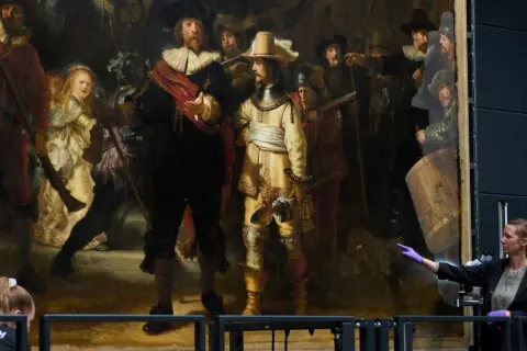 Restauratorin zeigt auf Rembrandts "die nachtwache maler", ein Meisterwerk der Malerei, das gerade untersucht wird.
