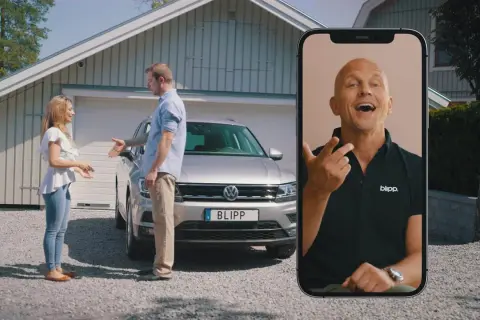 Kvinna och man diskuterar en bil med fel. En man på en mobilskärm ger råd om hur man kan byta in bil med fel.
