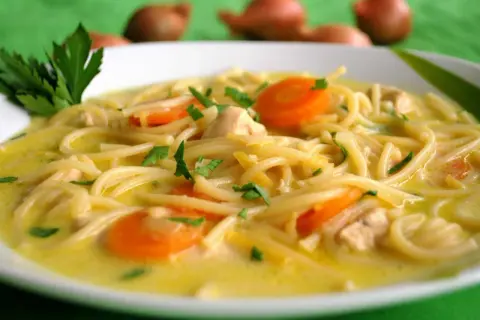 Aromatyczna zupa cytrynowa z kurczakiem, makaronem i marchewką, udekorowana natką pietruszki. Idealna na chłodne dni.