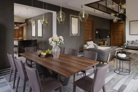 Nowoczesny salon i jadalnia w jednym pokoju. Drewniany stół z krzesłami, w tle szara kanapa i kuchnia.
