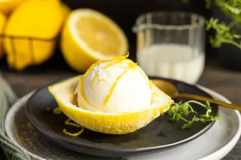 Erfrischendes Buttermilch Zitrone Eis, serviert in einer ausgehöhlten Zitrone, garniert mit Zitronenschale.