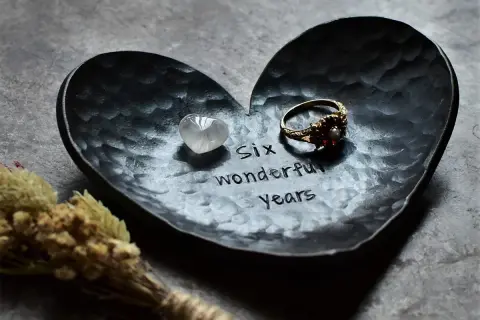 Czarna, sercowata tacka z wygrawerowanym napisem "Six wonderful years", pierścionkiem i kamieniem.