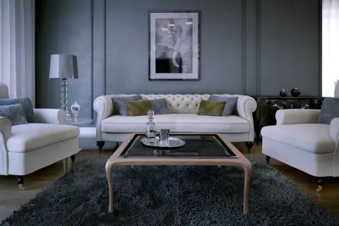 Eleganckie wnętrze z sofą i fotelami. Widać tu jak połączenie złota i srebra we wnętrzu, np. w lampie i ozdobach.