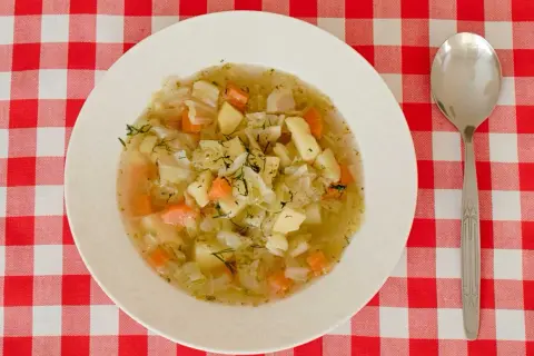 Aromaticzna zupa ze słodkiej kapusty z ziemniakami i marchewką, posypana świeżym koperkiem.
