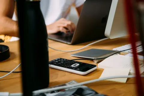 Biurko z laptopem, kalkulatorem i notatkami. Idealne miejsce do pracy zdalnej, gdzie sprzedaż detaliczna prowadzona przez domy sprzedaży wysyłkowej lub inte... jest na wyciągnięcie ręki.