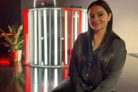 Michelle Kadir ler framför en ljusinstallation med röda och vita rör.