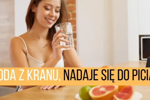 Uśmiechnięta kobieta pije wodę z kranu, zastanawiając się nad obecnością mikroorganizmów w wodzie pitnej.