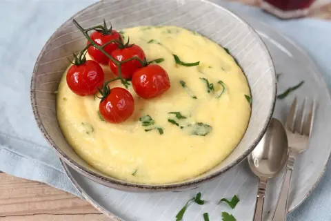 Cremige Polenta, ein italienisches Rezept, garniert mit Kirschtomaten und Petersilie.