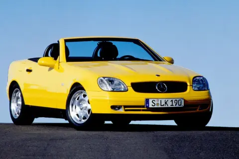 Żółty kabriolet Mercedes SLK na tle błękitnego nieba.