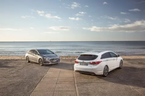 Dwa Hyundai i40, sedan i kombi, stoją nad brzegiem morza. Wiele pozytywnych hyundai i40 opinie potwierdza ich wszechstronność.
