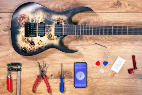Gitarre mit Werkzeug und Handy-App zur Einstellung des Saitenabstands.