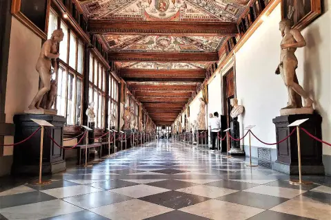 Corridoio della **Gallerie des Offices Florence**, con statue classiche, soffitto affrescato e pavimento a scacchi.