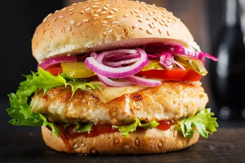 Domowy hamburger z kurczakiem, serem, sałatą, pomidorem, ogórkiem i czerwoną cebulą.