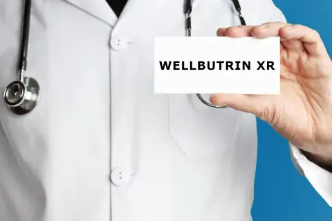 Lekarz w białym kitlu prezentuje kartkę z napisem WELLBUTRIN XR.