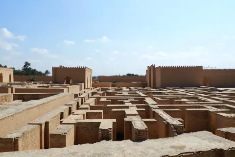 Ruinas de ladrillo de la antigua Babilonia, un laberinto de muros bajo un cielo azul.