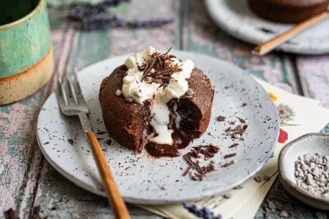 Ein Schokoladen-Lava-Kuchen mit flüssigem Kern, garniert mit Schlagsahne und Schokostreuseln. Ein perfektes Lava cake rezept für Genießer.