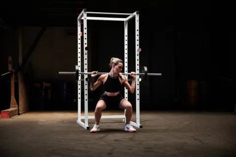 Kvinna utför squats med stång i ett gym.