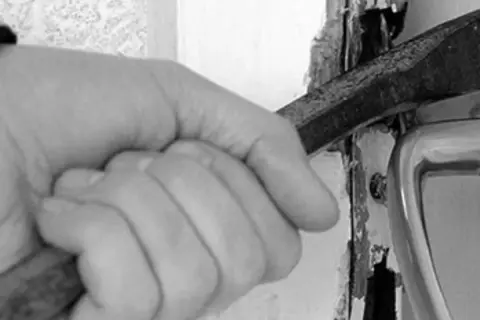 Mano con cincel forzando una puerta, una imagen que evoca la problemática de los okupas en España.