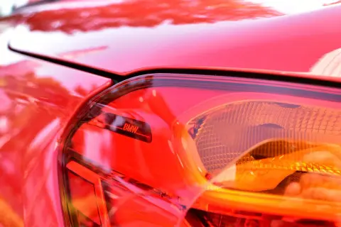 Czerwone BMW, błyszczące w słońcu, symbolizuje dynamiczna jazda co to znaczy – moc i precyzję na drodze.